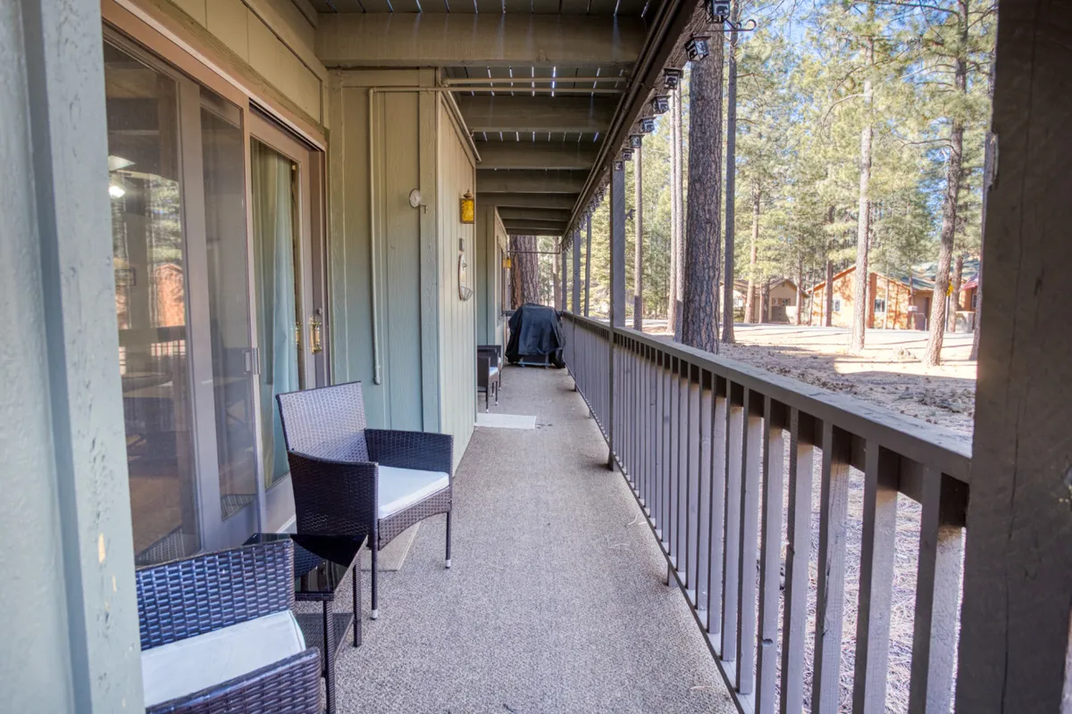 This image captures an outdoor balcony area with comfortable chairs and a grill, set against a backdrop of nature. The inviting setup encourages outdoor dining, relaxation, and an appreciation of the tranquil environment, perfectly blending the comforts of home with the beauty of the surrounding landscape.