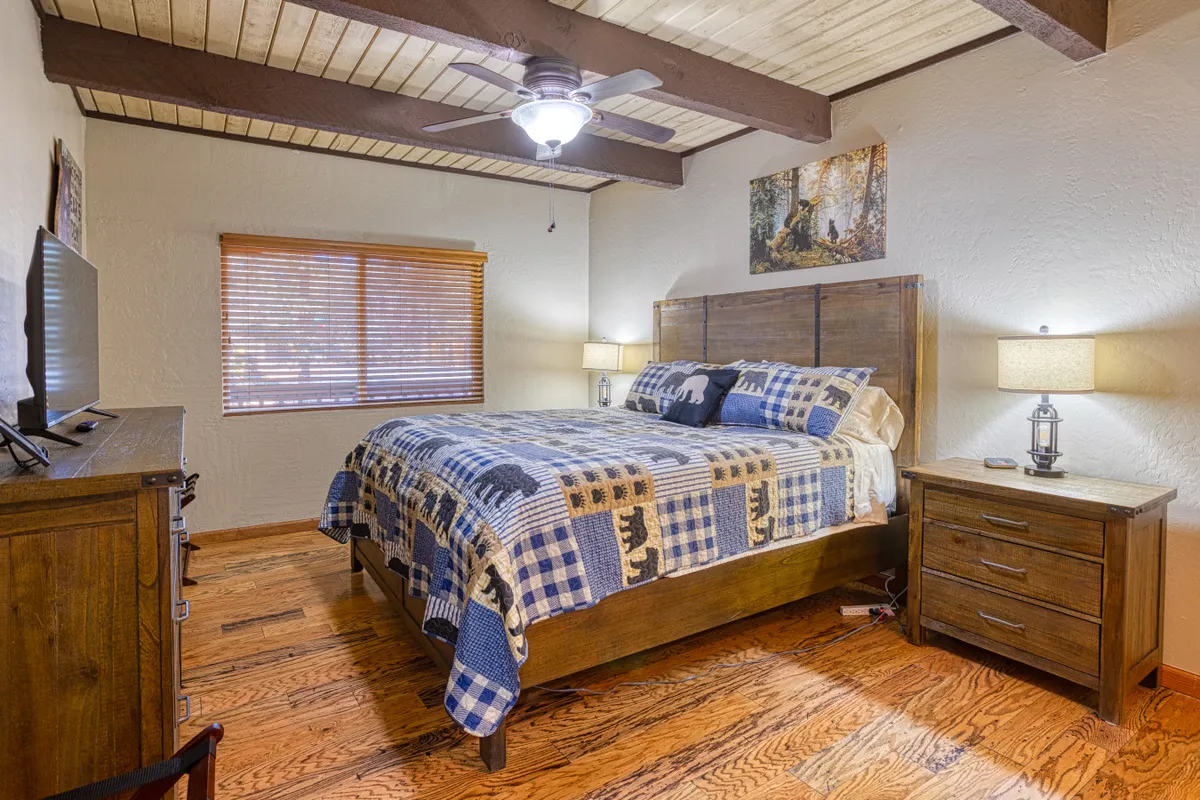 Another comfortable bedroom scene showing a bed with patterned bedding, wooden furniture, bedside lamps, and artwork on the wall. Natural light filters through, and the setting feels homey—ideal for unwinding after exploring the outdoors.